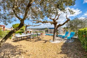 a patio with chairs and a table and a tree at Charmante location vacances in Montagnac