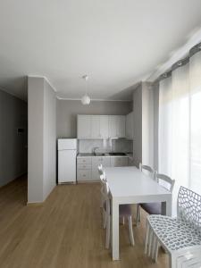 a white kitchen with a white table and chairs at Radhima Beach Apartments in Vlorë