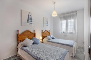 two beds in a room with white walls at Duplex a 9 min De Bajo de Guia in Sanlúcar de Barrameda
