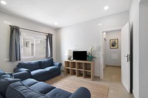 a living room with a blue couch and a tv at Skipper House in Loulé