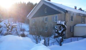 a house covered in snow with the sun behind it at Gîte Les Chamois 15 Personnes in Les Rousses +4 photos
