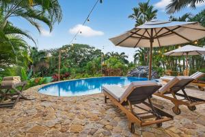 a pool with two chairs and an umbrella at Ocio Villas Mal Pais in Santa Teresa Beach