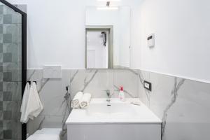 a white bathroom with a sink and a mirror at P&P Apartment in Forio d'Ischia +2 photos