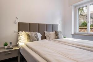 ein großes Bett mit weißen Laken und Kissen in einem Schlafzimmer in der Unterkunft Cà Granda Brenzone in Brenzone sul Garda