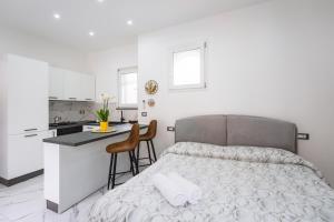 a white bedroom with a bed and a kitchen at P&P Apartment in Forio d'Ischia