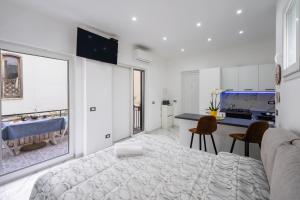 a white bedroom with a bed and a kitchen at P&P Apartment in Forio d'Ischia