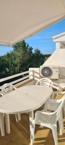 a white table and chairs on a balcony at Villa Orchidée - Coves Noves in Punta Grossa