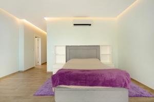 a bedroom with a bed with a purple blanket at Casa Jolie in Ponta do Sol