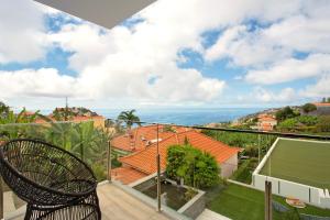 a chair on a balcony with a view of the ocean at Casa Jolie in Ponta do Sol
