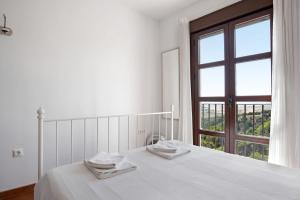 a white bedroom with a bed and a window at Cobijadas75 Janda in Vejer de la Frontera
