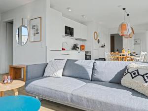 a living room with a blue couch and a kitchen at Apartment Penthouse Dümmerblick - 619 by Interhome in Lembruch
