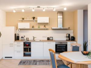a kitchen with white cabinets and a table and chairs at Ferienwohnung Storchenaue in Wächtersbach
