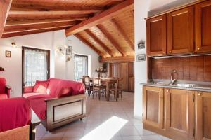 a kitchen and living room with red furniture and wooden ceilings at Verger Plein Soleil in Saint-Pierre