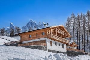 a building in the snow with mountains in the background at Apartment Mittermanting Villnöss in Villnoss