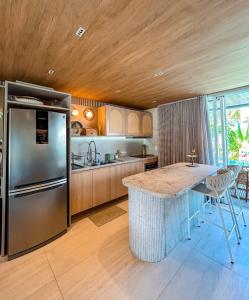 a kitchen with a stainless steel refrigerator and a table at Casa Verde Mar Naluum in Passo de Camarajibe