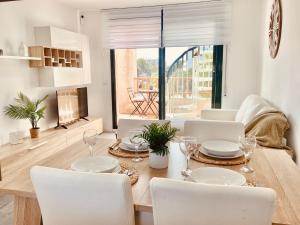 a dining room with a table with white chairs and a dining room at Atico Solarium La Cala in Miami Platja