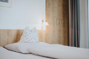 a bed with white sheets and pillows on it at Unterhauserhof App A in Valdaora