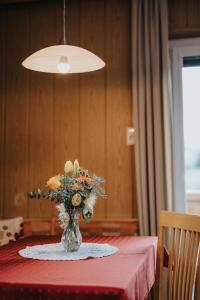 a vase of flowers on a table with a red table cloth at Unterhauserhof App A in Valdaora