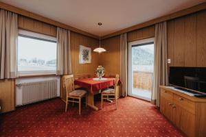 a room with a red table and chairs and a television at Unterhauserhof App A in Valdaora