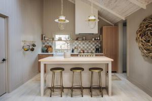 a kitchen with a island with three bar stools at The Townie Cottages by Juniper Holiday + Home in Union Pier