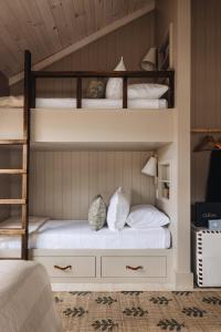 a bedroom with two bunk beds with white pillows at The Townie Cottages by Juniper Holiday + Home in Union Pier