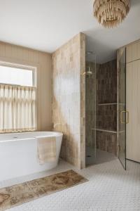 a bathroom with a tub and a shower and a chandelier at The Townie Cottages by Juniper Holiday + Home in Union Pier +120 photos