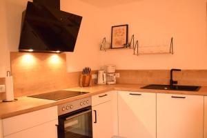 a kitchen with white cabinets and a sink and a stove at Fewo Tenne in Menslage