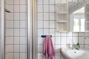 a white tiled bathroom with a sink and a mirror at Möve Aba Bungalow 63 in Rerik +20 photos