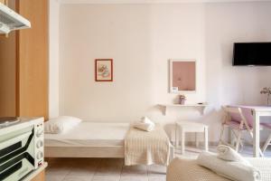 a small white room with a bed and a table at Nontas Home 27 in Kalamitsi