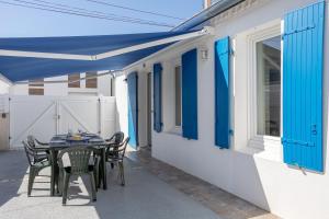 a table and chairs under a blue canopy on a patio at Maison proche océan - 6 pers in Bretignolles-sur-Mer