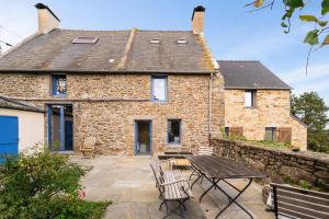 a stone house with a table and benches in front of it at Maison Plage Verger Cancale in Cancale