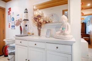a white dresser with a statue on top of it at Casa da Mãe Maria in Buarcos +16 photos