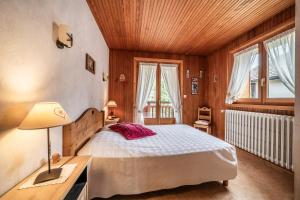 a bedroom with a bed and a desk and windows at Appartement chalet - Le Vnipi in Abondance