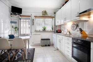 a kitchen with white cabinets and a table and chairs at Casa da Mãe Maria in Buarcos