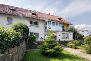 a white house with a fence and a yard at Ferienwohnung Wiesenschneiders in Freiensteinau