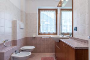 a bathroom with two sinks and a toilet and a window at Appartamento Adamello Casa Lucia in Pinzolo +22 photos