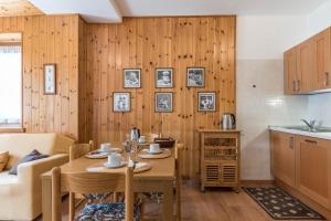 a kitchen and living room with a wooden wall at Appartamento Adamello Casa Lucia in Pinzolo