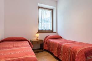 two beds in a room with a window at Appartamento Adamello Casa Lucia in Pinzolo