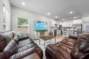 a living room with two leather couches and a kitchen at Marigold House in Foley