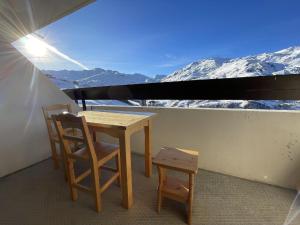a table and two chairs on a balcony with snow covered mountains at Brelin - Combes in Les Menuires