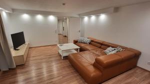 a living room with a brown couch and a tv at Ferienwohnung Burgstraße in Fuldatal