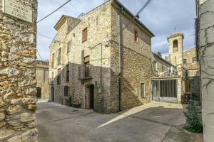 an old stone building with a church in the background at Can Roca in Montiró