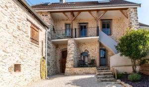 a stone house with a balcony and a courtyard at Gîte La voisine in Venteuil