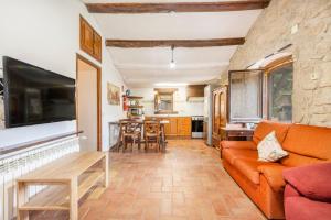 a living room with an orange couch and a tv at La Caseta De Sant Grau in Navés