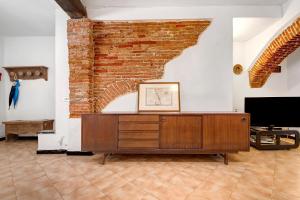 a living room with a brick wall and a tv at Appartamento Piazza Bertamino in Bonassola