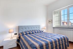 a bedroom with a bed with a blue comforter and a window at Villa Lucia in Ameglia