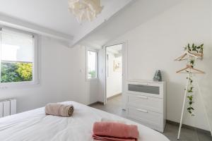 a white bedroom with a bed and a mirror at Bois Flottés - Maisonnette 700m mer in Pornic