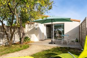 a green umbrella on a patio with a table and chairs at Bois Flottés - Maisonnette 700m mer in Pornic