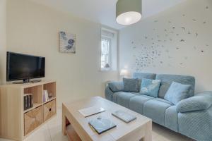 a living room with a blue couch and a tv at Côte d'emeraude in Saint-Benoît-des-Ondes