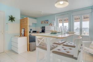 a kitchen with blue walls and a white table and chairs at Côte d'emeraude in Saint-Benoît-des-Ondes +15 photos